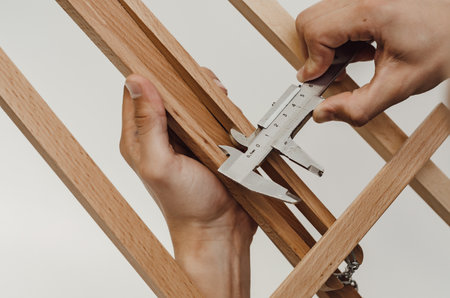 Measurement of sizes by means of a caliper. Carpenter's hands measure the width of bar.