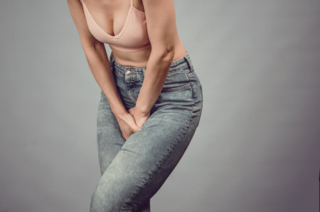 Women's health. Pain in the abdomen, female organs. Silhouette of woman suffering from abdominal pain. Hands between legs.の写真素材