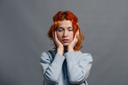 Stylish mysterious woman with red hair. Lights on hair. Eyes closed.. Gray backgroundの写真素材