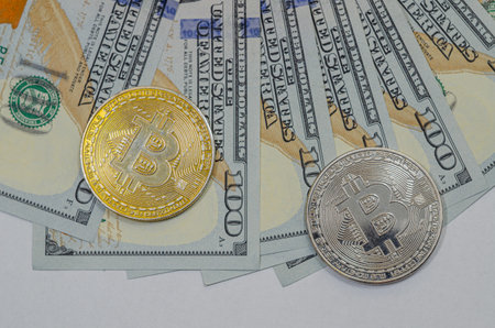 Gold and silver Bitcoin coins on American paper dollar bills.の写真素材