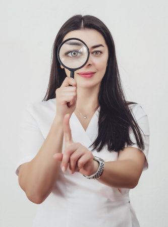 The woman looks into the magnifying glass. one eye enlargedの写真素材