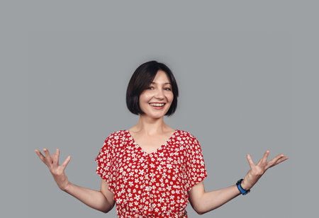 Dark-haired optimistic woman raises her hands in joy and surprise. Happy in anticipation of the surprise.の写真素材