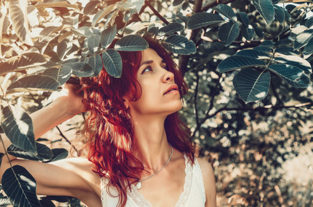 Portrait of a red-haired young girl among the trees in the gardenの写真素材