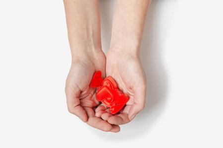 Female hands hold many small red hearts in their palms. white backgroundの写真素材