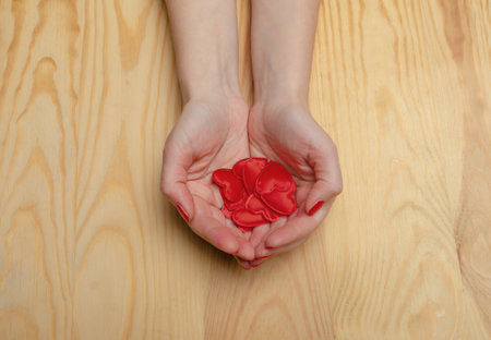 Many red hearts in women's palms. wooden background. Red nail polish