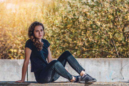 Resting teenage girl sitting on ground. dream eyes. Sunset background.の写真素材
