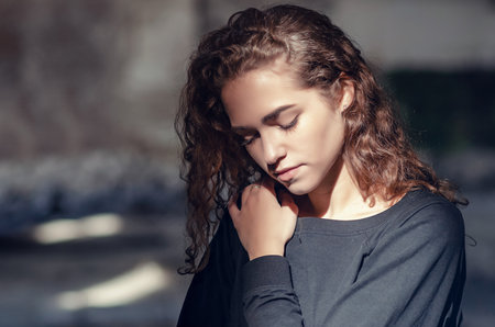Lovely girl close-up portrait, face lit by ray of sunshine, contrasting photo.の写真素材