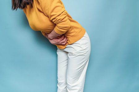 A young woman feels pain in the lower abdomen. Need to pee. Hands pressed in lower abdomenの写真素材