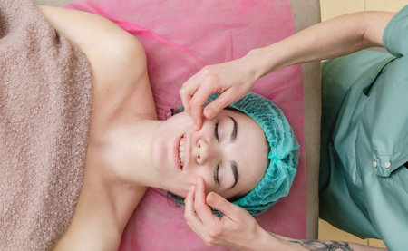 Top view of female face in cosmetic cap. The client is waiting for pleasure of facial massage.の写真素材