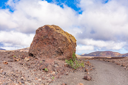 Large stone near road leading to mountains. mountain landscape under white cloudsの写真素材