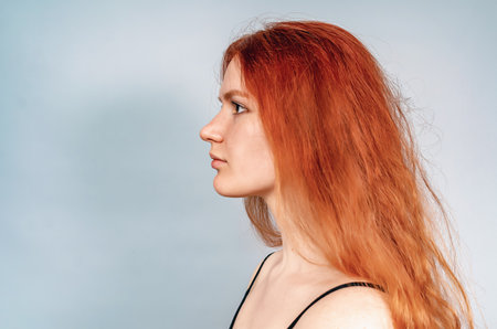 Profile of serious red-haired girl in a black T-shirt. Long hair, brown eyes.