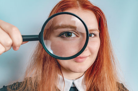 Smiling woman holds magnifying glass near her eye. Research, eye diseases, treatment.の写真素材