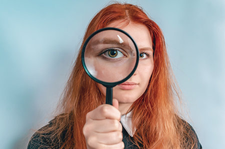 Magnifying glass. Woman's face through magnifying glass. big eyes. Research, choice concept.の写真素材
