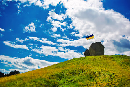 Ukrainian flag on a large stone on a mountain under a cloudy sky