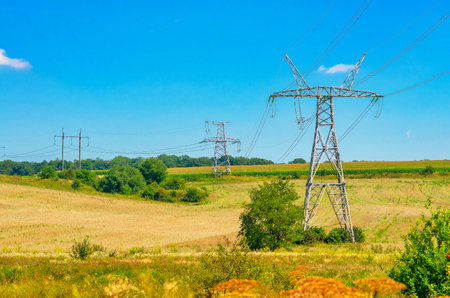 High-voltage electric poles in field in summer. Electric energy, energy supplyの写真素材