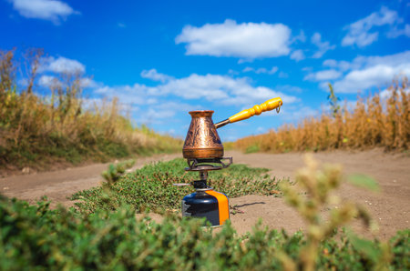 Copper cezve on a gas burner outdoors under blue sky. Coffee in natureの写真素材