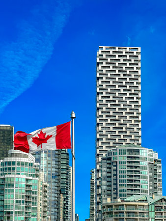 Flag of Canada on the background of modern houses and blue skyの写真素材