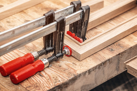 Carpenter clamps are fixed to boards. Gluing joinery in the workshopの写真素材