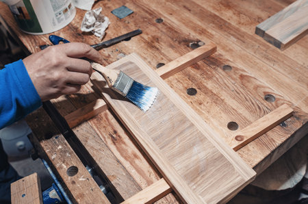 Varnishing a wooden drawer, carpentry workshop. Varnish is applied to a wooden board with a brushの写真素材