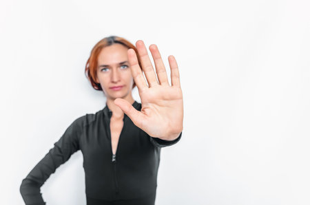 Blurred portrait of young lady extending hand forward saying no enough. Focus on female palm close...