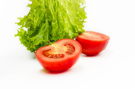 Green fresh lettuce leaves with sliced juicy tomatoes isolated on white background. Close upの写真素材