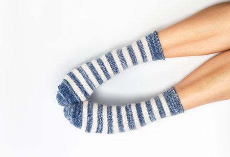 Warm fluffy striped socks on bare female feet. The concept of warmth and restの写真素材