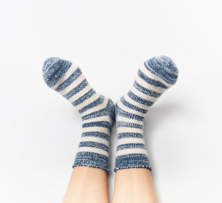 Warm fluffy striped socks on bare female feet. The concept of warmth and rest