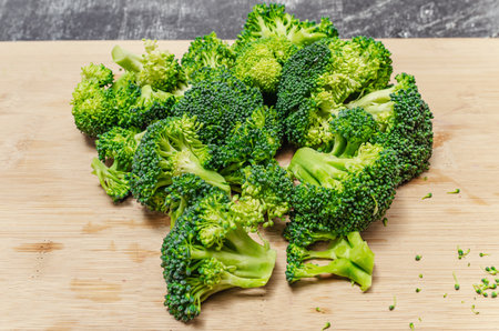 Fresh green broccoli divided into florets on wooden board. Appetizing vegetable for healthy diet.の写真素材