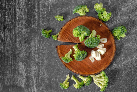 Inflorescences of green broccoli and garlic - still life image. Wooden natural round stand. Top viewの写真素材