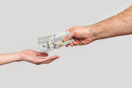 Male hand sends banknotes to woman's hand. Transfer of money, sponsorship, financial relations.