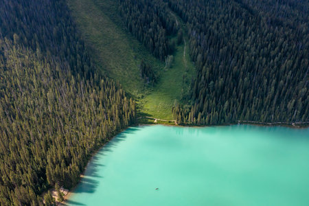 Part of lake in forest that rises into mountains. Canada, Valley of Ten Peaks. Soothing photo.の写真素材