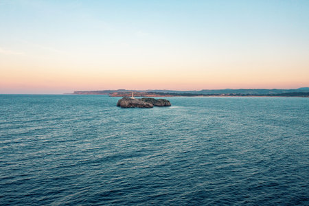 A small lighthouse on a stone rock in the sea near the coastの写真素材