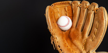 Baseball glove with white baseball on black background. High-quality close-up photo. Copy spaceの写真素材