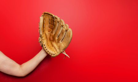 Baseball glove on woman's hand. Red background, copy space. Active sport, championship, victoryの写真素材