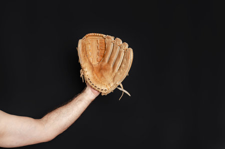 Baseball glove on man's hand. Black background. Active sports, championship, victory, competitionの写真素材