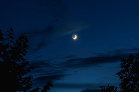 The growing moon on the background of the blue sky at night. Astrophotoの写真素材