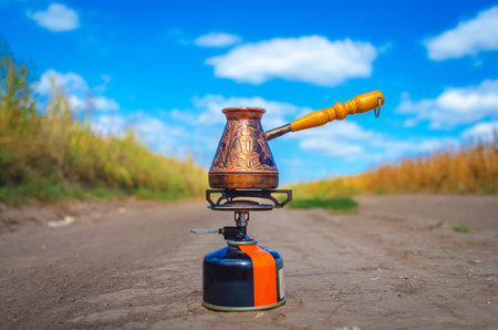 Copper cezva turka for making coffee stands on a tourist gas burner. Making coffee outdoorsの写真素材