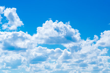 Clear blue sky with cumulus white clouds evokes feeling of tranquility. Sun rays through cloudsの写真素材