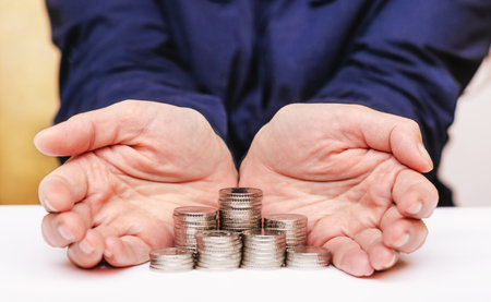 Woman palms are open, protecting the money coins are stacked in stacksの写真素材