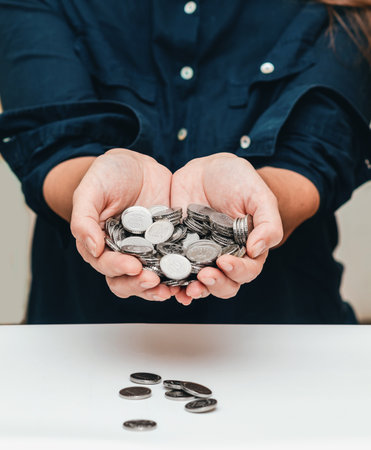 woman's hands hold a large amount of money in coins