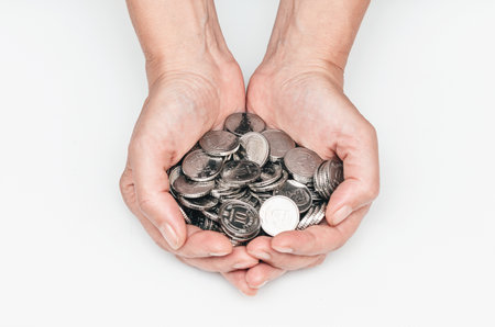 Female hands hold many silver coins in their palmsの写真素材