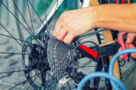 Bicycle chain system. Man's hand tightens the chain on bicycle. Bicycle repair. Maintenanceの写真素材