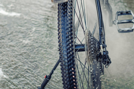 Part of bicycle after washing at car wash. Clean wet wheel with spokes, chain and pedal. Activityの写真素材