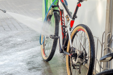 Powerful stream of water washes the bicycle at car wash. High pressure pump. Maintenanceの写真素材