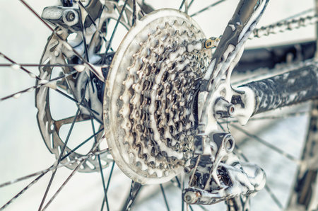 Enlarged bicycle wheel at car wash. Spokes, chain. Washing bicycle with jet of foam. Maintenanceの写真素材