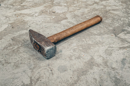 Old steel hammer on concrete floor. Strong hammer with wooden handle. Vintage workshop backgroundの写真素材