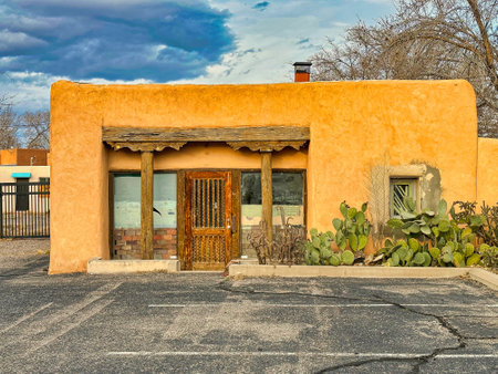 ALBUQUERQUE, NEW MEXICO, USA - March 8, 2023. Old abandoned wooden yellow clay house. Wooden windows and doors. Cacti near houseのeditorial素材