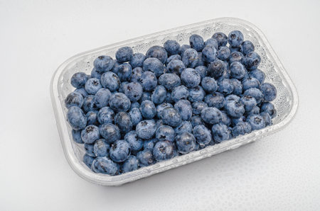 Transparent container with fresh blueberries. Isolated on white. Studio light. Vitamins, immunityの写真素材