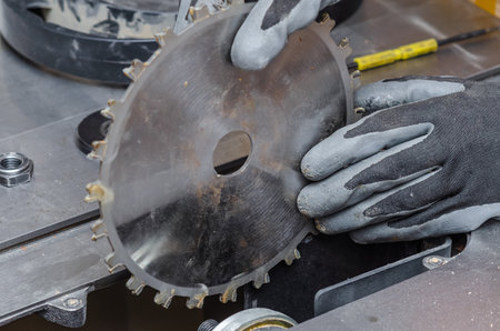 carpenter replaces a circular saw in a machine tool. Replacing the saw in the carpentry shopの写真素材