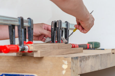 Fastening carpentry clamps on a wooden frame in a carpentry workshop, gluing boardsの写真素材